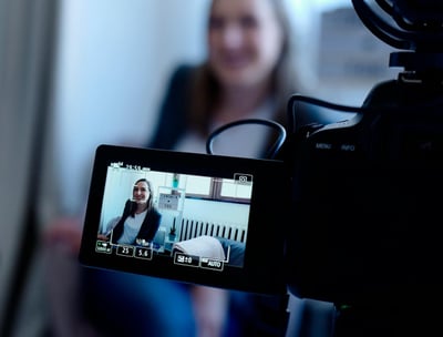 Interior shot of smiling woman being video recorded