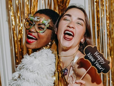 femmes souriantes portant des accessoires festifs dans une cabine photobooth, célébrant le Nouvel An