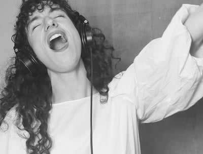 photo en noir et  blanc de aude fy en train de chanter avec casque sur les oreilles