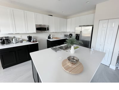 Modern organized kitchen with white cabinets, stainless steel appliances, and clutter-free counters.