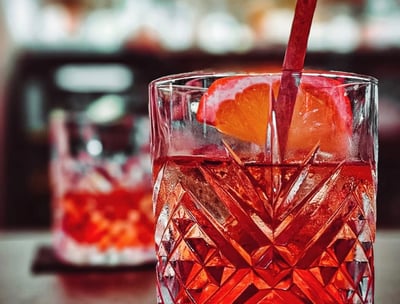 a glass of red wine with a strawberries and oranges