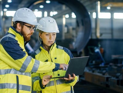 two people in safety gear standing in a factory