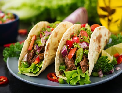 Two halal tacos filled with seasoned meat and toppings, without sauces.