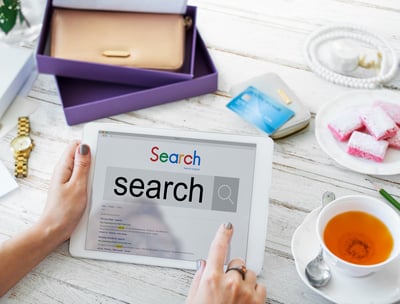 Tablet con la palabra search en pantalla, rodeada de objetos cotidianos como taza de té y cuaderno