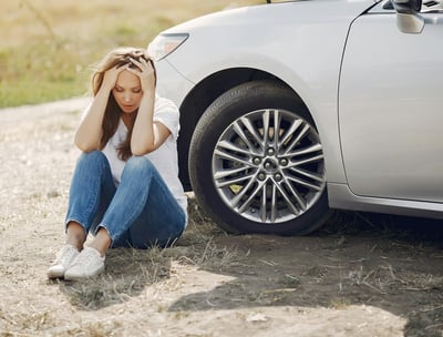 a woman sitting on the ground next to a car