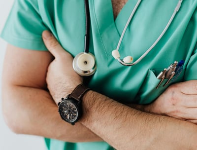 a man in a green scrubsuit with a stethoscope attached to his