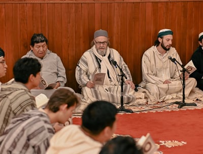 a group of men sitting on a carpeted area remembering Allah