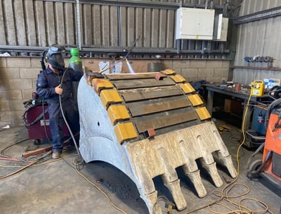 a man welding a piece of wood with a welding machine
