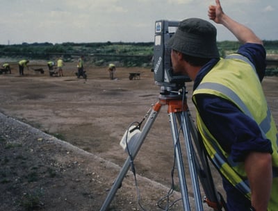 a man in a yellow vest and a camera on a tripod