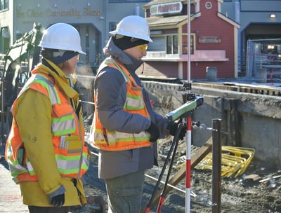 two men in safety vests standing in front of a building