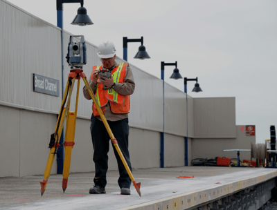 a man in a hard hat and safety vest using a tripod