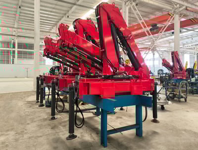 Production line: Red SQZ68B.3 (3.2T) articulating knuckle boom cranes on blue stands, pre-vehicle mounting.