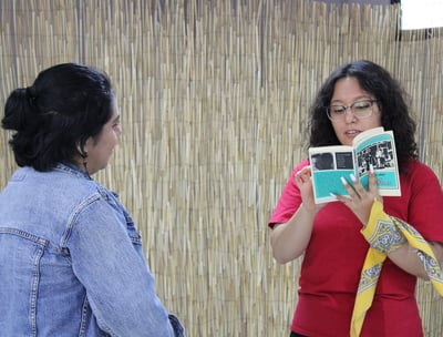 Una mujer leyéndole en voz alta a otra mujer