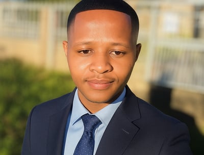 a man in a suit and tie standing in front of a fence