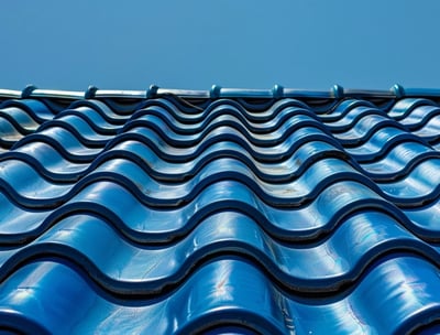 A Clean and wavy blue tile roof on a clear day reflects the same clear blue sky