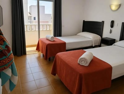 Habitación con balcón en Hotel San Vicente, Conil. Dos camas individuales, luz natural y acceso a te