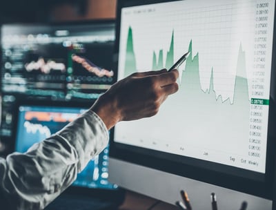 a man is holding a pen and pointing at a chart on a computer screen