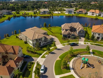 Aerial real estate photography of luxury homes by a lake and park in an upscale neighborhood