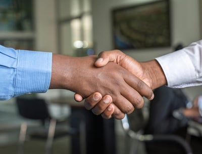 two men shaking hands with one holding a handshakt