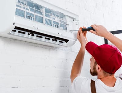 a man in a red hat is fixing a air conditioner