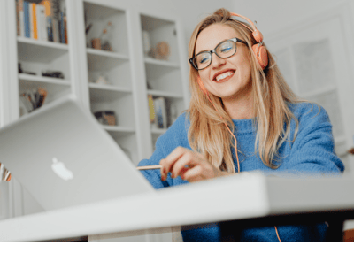 a woman wearing a blue sweatshirt and headphones, sitting at a desk