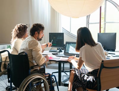 Equipe diversa em reunião estratégica, incluindo profissional cadeirante com produtividade