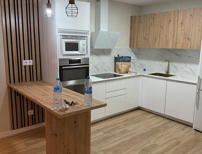 Cocina moderna con barra, muebles de madera y electrodomésticos.