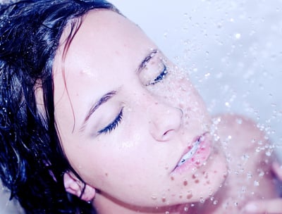 a woman in the shower letting the water hit her face