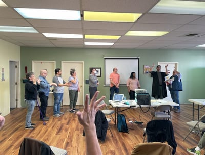 Hand raised in center of photo with people lined up in the background