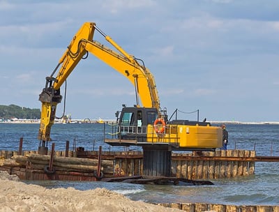 excavator holding logs for dock construction