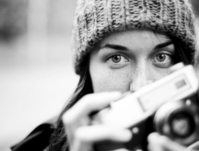 Student in fine art photography courses holding a vintage camera, black and white portrait.