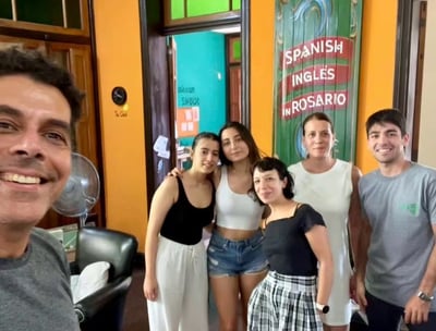 Group of people in a language school in Rosario, with a sign that reads ‘SPANISH INGLES in ROSARIO’