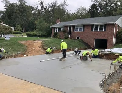 a group of men in yellow jackets and yellow jackets working on a concrete slab