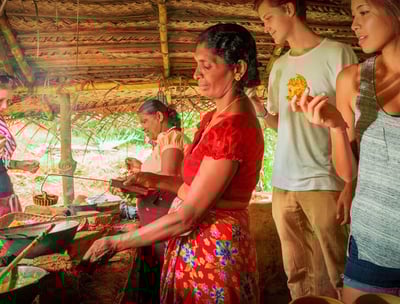 a woman cooking food in a hut with a man and a woman
