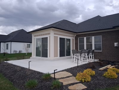 New patio enclosure with two large sliding-glass doors leading out onto a concrete slab patio.