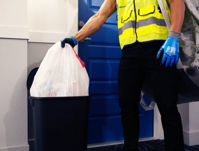 A man picking up trash from a resident's doorstep during valet trash services.