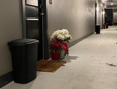 A valet trash bin standing outside of a resident's apartment door.