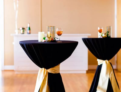 Mesa de coctel para evento con mantel negro y decoracion dorada