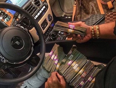 a man sitting in a car with a bunch of money