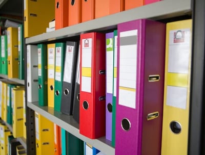 a bunch of folders on a shelf in a library