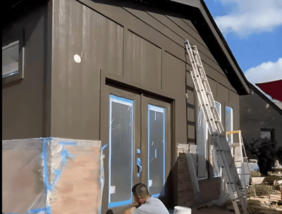 a man is painting a house with a blue sky