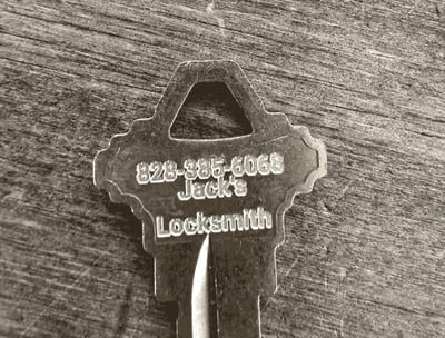 Metal key engraved with "Jack's Locksmith" and phone number, representing professional locksmith services.
