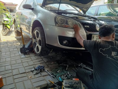 a man working on a VW car with a open hood