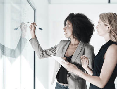 mulheres do mundo corporativo escrevendo em quadro