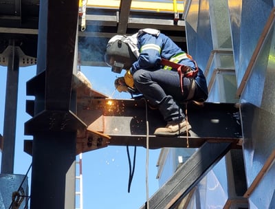 a man in a helmet welding a metal structure