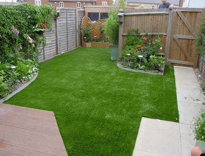 a backyard patio with a small garden and a wooden deck