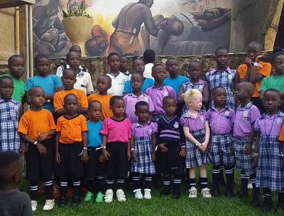 a group of children and adults standing in front of a large painting of a painting