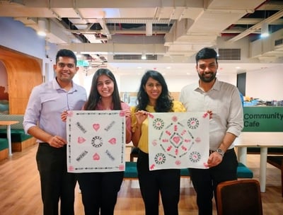 a group of employees standing around a table with their artwork