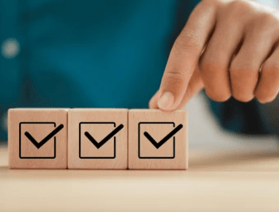 Close-up of hand placing a checklist block, representing quality control in product sourcing and ins