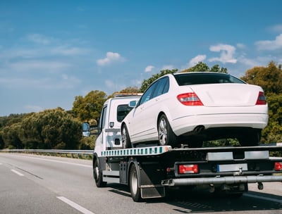 a white car is being towed on a flatbed
